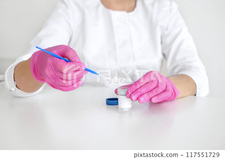 A gynecologist in pink gloves with a brush for taking a swab from the cervical canal for cytological abnormalities 117551729