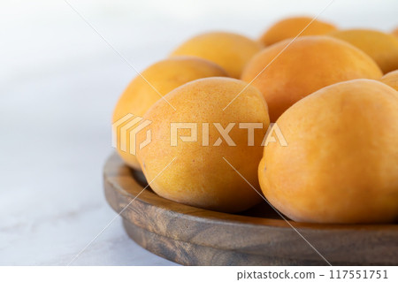 Ripe apricots on a wooden plate, close-up Ripe apricots on a wooden plate, close-up 117551751