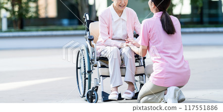 Senior woman in a wheelchair and her caregiver 117551886