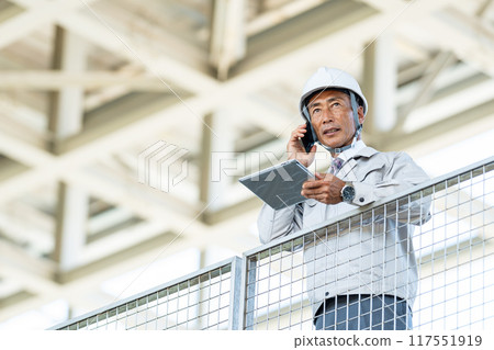 Male worker at construction site, smartphone 117551919