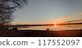 A sunset over a serene lake with people enjoying the view 117552097