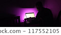 Young man silhouette sitting computer laptop in studio on violet background 117552105