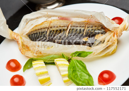 Gourmet baked mackerel in parchment with lemon slices, basil, and cherry tomatoes 117552171