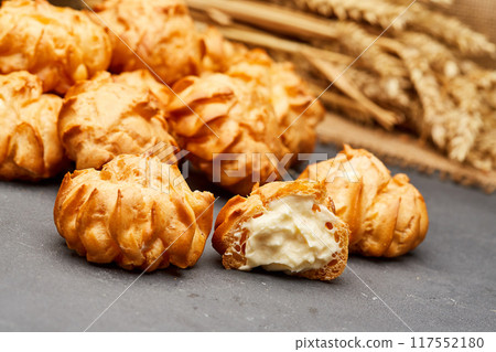 Delicious cream-filled profiteroles, golden and crisp, perfect for a sweet dessert treat Delicious cream-filled profiteroles, golden and crisp, perfect for a sweet dessert treat 117552180