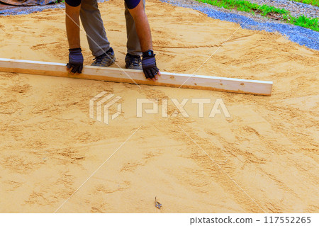 Using level for leveling sand when preparing platform for installation of swimming pool in backyard Using level for leveling sand when preparing platform for installation of swimming pool in backyard 117552265