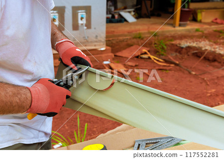 Before installing plastic vinyl siding, worker uses of scissors to cut it to size Before installing plastic vinyl siding, worker uses of scissors to cut it to size 117552281