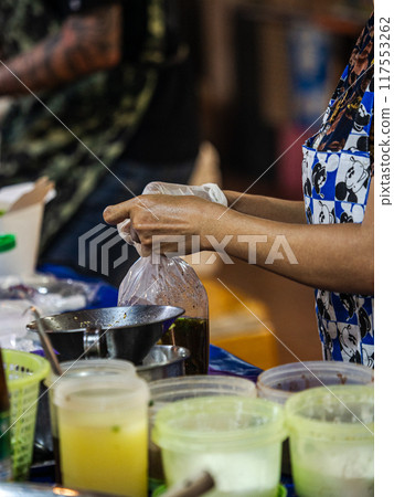 Street Vendor Filling Order at Night Market 117553262