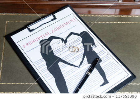 A prenuptial agreement with a silhouette of a couple and wedding rings, symbolizing marital contracts and legal preparation. 117553390