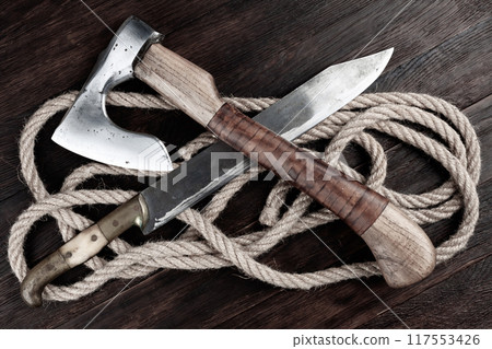 small axe with bowie knife and rope on wooden table 117553426