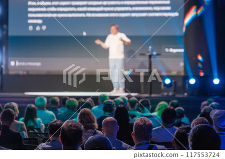 Public speaker presenting at large conference with audience Public speaker presenting at large conference with audience 117553724