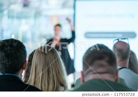 Audience listening to a business presentation in a conference room 117553728