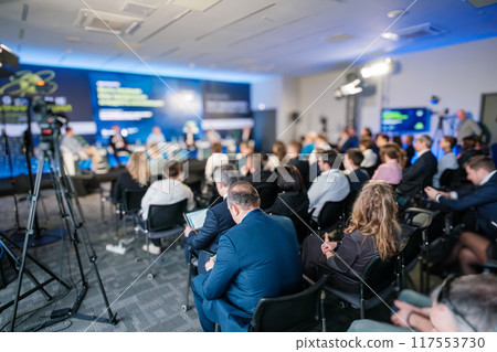 Business conference with a diverse panel and audience in a modern hall 117553730