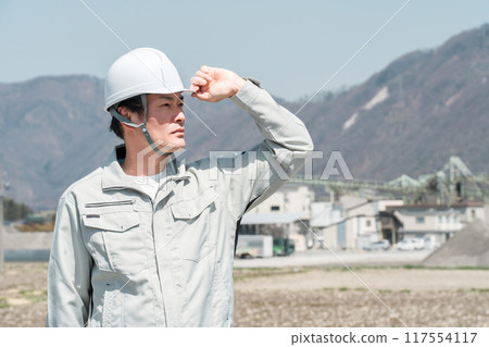 Asian male worker wearing work clothes and a helmet 117554117