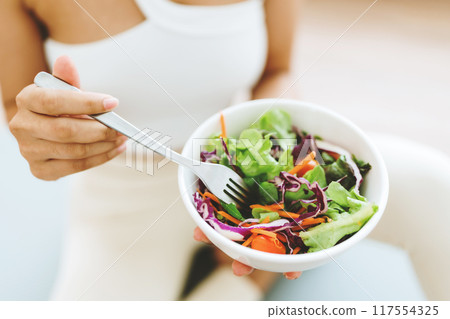 Young Asian woman holding salad bowl and looking at camera Young Asian woman holding salad bowl and looking at camera 117554325