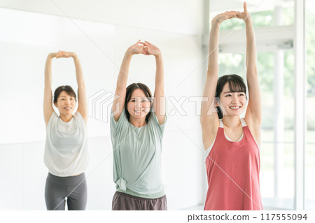 Smiling women doing stretching and flexibility exercises at the gym Smiling women doing stretching and flexibility exercises at the gym 117555094