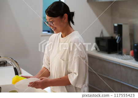 A woman washing dishes in the kitchen (housework, housewife). A woman washing dishes in the kitchen (housework, housewife). 117555423