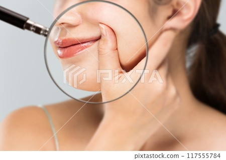A magnifying glass is used to magnify the cheek of a woman having her pubic folds lifted. A magnifying glass is used to magnify the cheek of a woman having her pubic folds lifted. 117555784