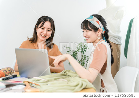 Asian female designer/stylist having a planning meeting while looking at a computer 117556593