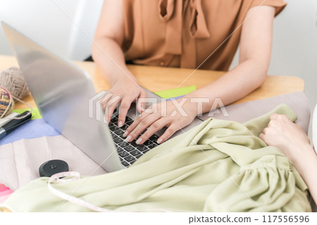 Asian female designer/stylist having a planning meeting while looking at a computer 117556596
