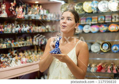 Happy young woman choosing statue of Spanish dancer among various souvenirs in gift shop in Barcelona Happy young woman choosing statue of Spanish dancer among various souvenirs in gift shop in Barcelona 117556810