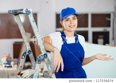 Woman foreman shows with her hand at a job well done on the repair of premises Woman foreman shows with her hand at a job well done on the repair of premises 117556874