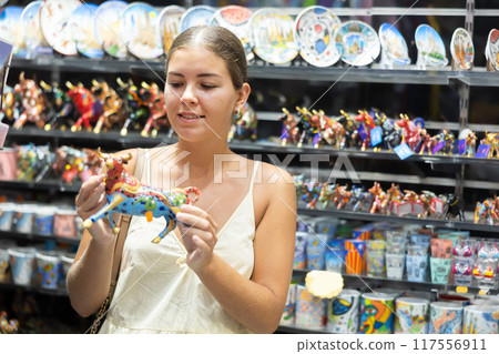 Female traveler buyer chooses ceramic ox, glass figurine of bull Female traveler buyer chooses ceramic ox, glass figurine of bull 117556911
