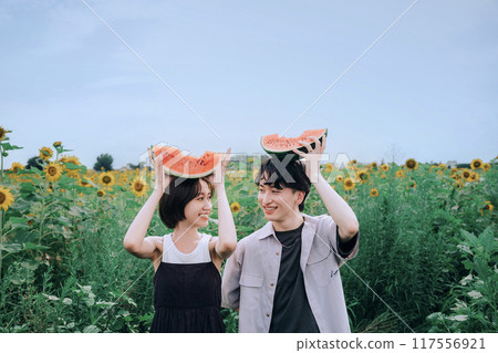 一對夫婦拿著西瓜在向日葵田裡拍照 117556921