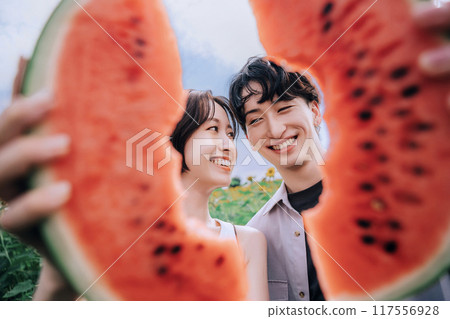 一對夫婦拿著西瓜在向日葵田裡拍照 117556928