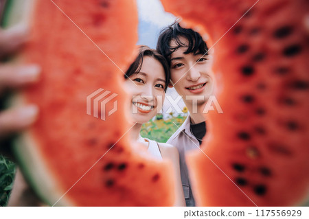 一對夫婦拿著西瓜在向日葵田裡拍照 117556929