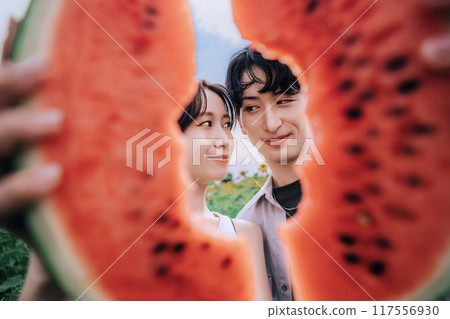 一對夫婦拿著西瓜在向日葵田裡拍照 117556930