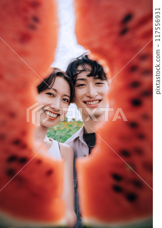 一對夫婦拿著西瓜在向日葵田裡拍照 一對夫婦拿著西瓜在向日葵田裡拍照 117556931