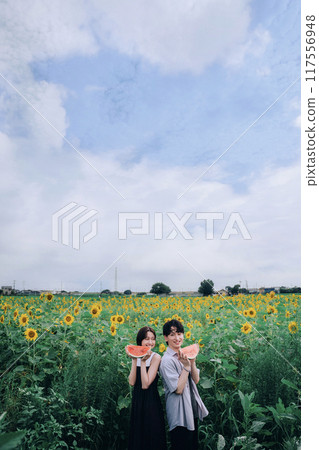 一對夫婦拿著西瓜在向日葵田裡拍照 117556948