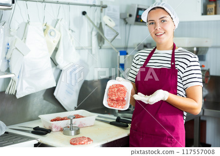 Female butcher demonstrating freshly formed beef hamburger patties Female butcher demonstrating freshly formed beef hamburger patties 117557008