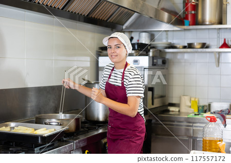 Female chef cooking dishes for sale in culinary department of supermarket 117557172