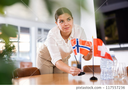 female assistant prepares conference room for diplomats of Switzerland and Norway female assistant prepares conference room for diplomats of Switzerland and Norway 117557236