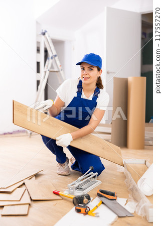 Young woman builder installing parquet 117557270