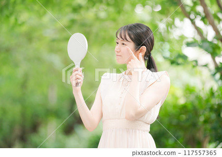 A woman watching a hand mirror 117557365