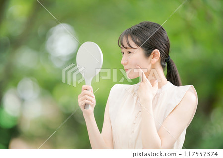 A woman watching a hand mirror A woman watching a hand mirror 117557374