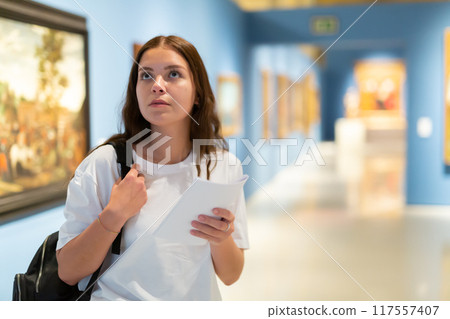 Thoughtful young girl in an art gallery studies works of art Thoughtful young girl in an art gallery studies works of art 117557407