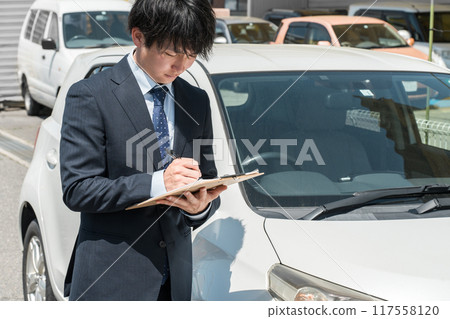 Salesman/appraiser using a checklist to assess and estimate a car 117558120
