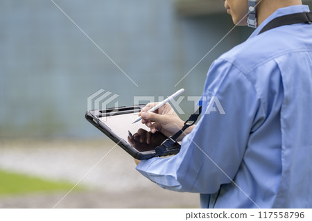 穿著工作服的男人的手在平板電腦上打字 117558796