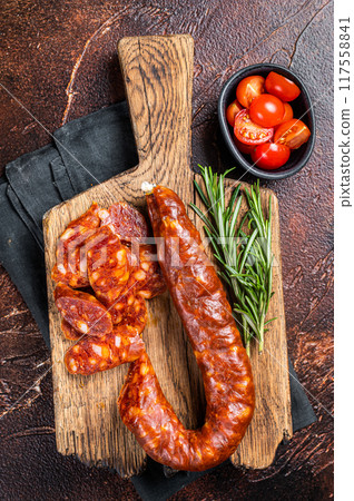 Dry cured Spanish Chorizo sausage, slices of meat with herbs and spices. Dark background. Top view 117558841