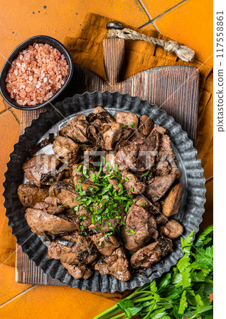 Roast chicken liver with onions and herb in a steel plate. Orange background. Top view Roast chicken liver with onions and herb in a steel plate. Orange background. Top view 117558861