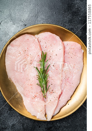 Uncooked Raw chicken chop breast fillets on a plate, poultry meat. Black background. Top view 117558865