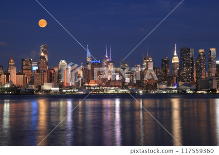 New York City skyline illuminated at dusk with orange full moon, view from Hudson River, USA New York City skyline illuminated at dusk with orange full moon, view from Hudson River, USA 117559360