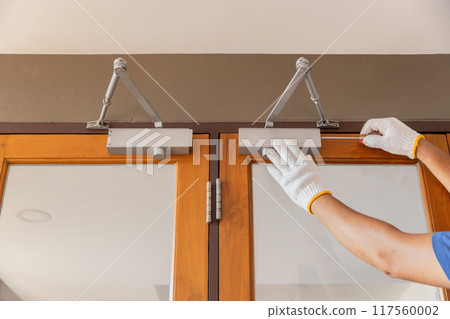 Handyman fixing door closer and adjust  hydraulic arm extended. 117560002