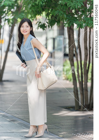 辦公區樹蔭下拿著平板電腦的女商人 辦公區樹蔭下拿著平板電腦的女商人 117560048