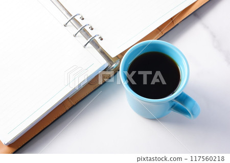 圖為一邊喝咖啡一邊在辦公桌前使用筆記本工作。 圖為一邊喝咖啡一邊在辦公桌前使用筆記本工作。 117560218