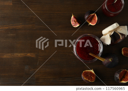 Glass jars with fig jam, spoon and cut figs on wooden background, space for text 117560965