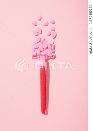 Wax granules for depilation with a razor on a pink background Wax granules for depilation with a razor on a pink background 117560983
